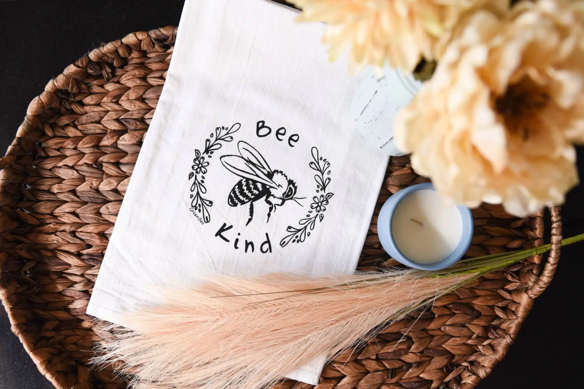 tea towel on a decorative try. tea towel says Bee kind with a floral band and a bee in the middle