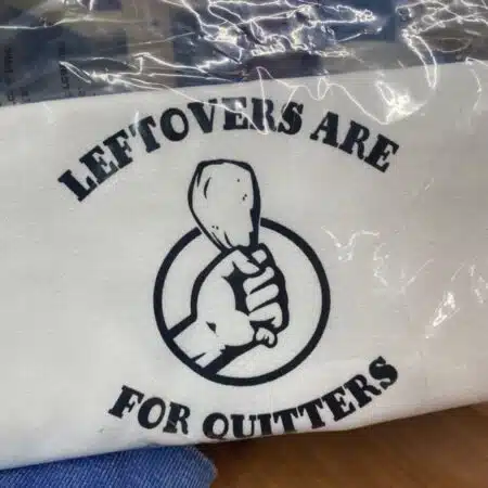tea towel with hand in a fist holding a chicken leg that says leftovers are for quitters slightly flawed kitchen tea towel