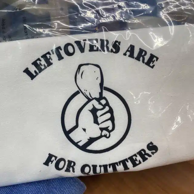 tea towel with hand in a fist holding a chicken leg that says leftovers are for quitters