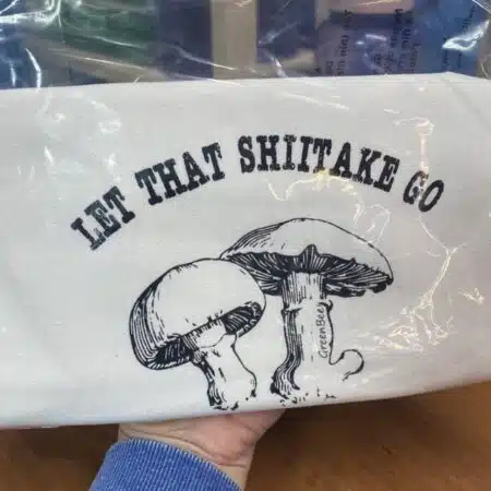 tea towel with mushroom and pun that says Let that shiitake go slightly flawed kitchen tea towel