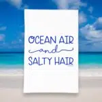 kitchen tea towel with blue lettering saying Ocean Air & Salty Hair kitchen tea towel